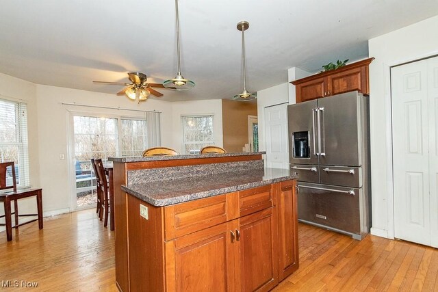 kitchen with ceiling fan, high end fridge, a center island, and light hardwood / wood-style flooring