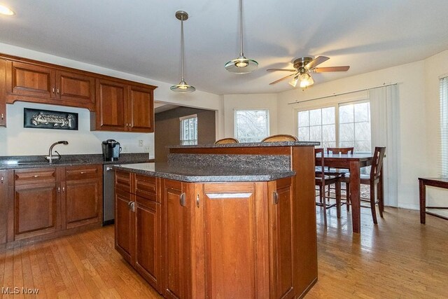 kitchen with light wood-type flooring, a center island, ceiling fan, and sink