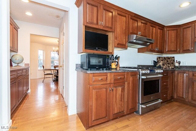 kitchen featuring dark stone countertops, a chandelier, stainless steel range oven, and light hardwood / wood-style floors