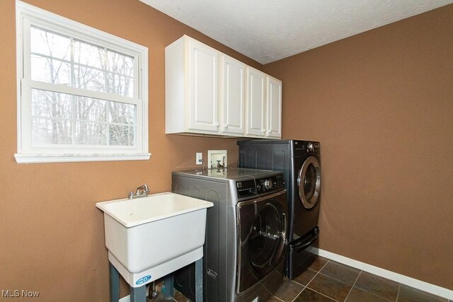 laundry room featuring cabinets, a textured ceiling, dark tile patterned floors, sink, and washer and dryer