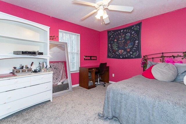 bedroom with ceiling fan, light colored carpet, and a textured ceiling