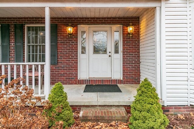 view of exterior entry with covered porch and brick siding