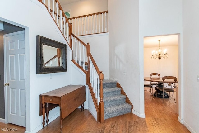 stairs featuring hardwood / wood-style floors and a chandelier