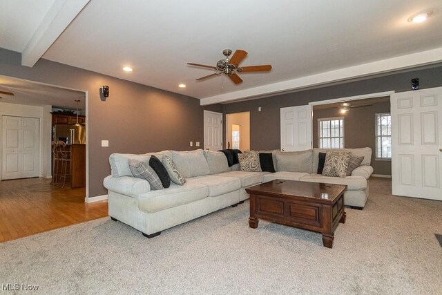 carpeted living room with beam ceiling and ceiling fan