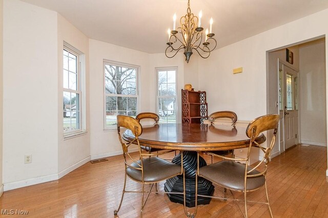 dining space featuring a notable chandelier, a healthy amount of sunlight, and light hardwood / wood-style flooring