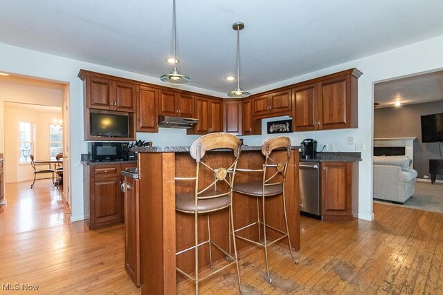 kitchen featuring a kitchen island, light hardwood / wood-style flooring, stainless steel dishwasher, and dark stone counters