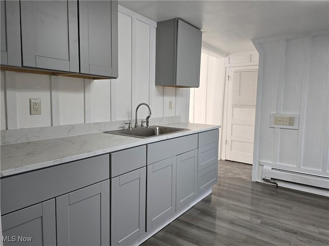 kitchen featuring gray cabinets, a baseboard radiator, sink, light stone countertops, and dark wood-type flooring