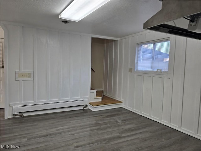 unfurnished room featuring a baseboard heating unit, dark hardwood / wood-style floors, and a textured ceiling