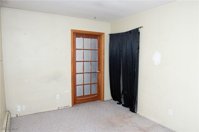 unfurnished room with a baseboard heating unit and light colored carpet