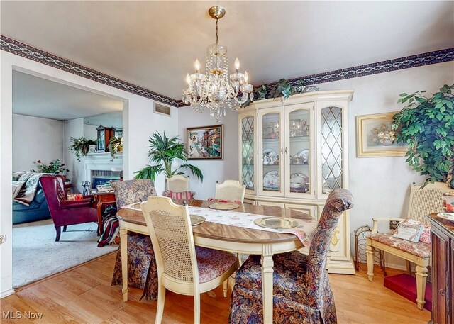 dining area featuring light wood-type flooring and a notable chandelier