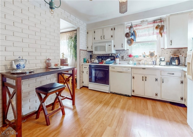 kitchen with white appliances, light hardwood / wood-style flooring, white cabinets, and tasteful backsplash