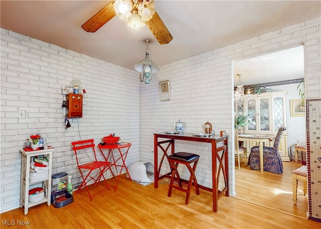 interior space with light wood-type flooring, ceiling fan, and brick wall