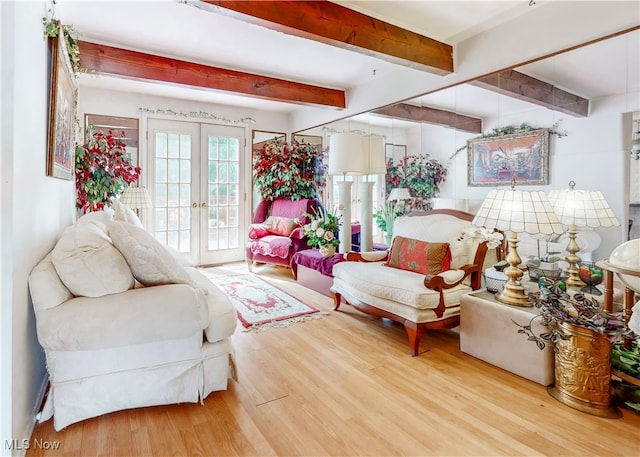 living room with beam ceiling, light wood-type flooring, and french doors