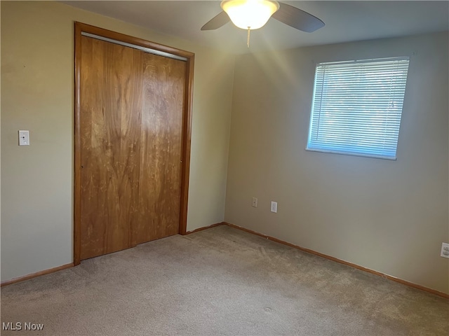 unfurnished bedroom featuring light carpet, ceiling fan, and a closet