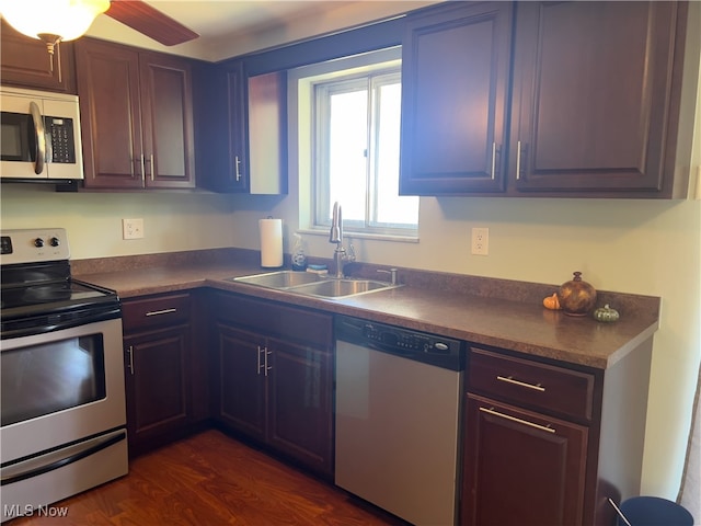 kitchen featuring appliances with stainless steel finishes, dark brown cabinets, dark hardwood / wood-style flooring, and sink