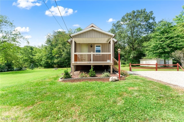 view of front facade featuring a front lawn, a garage, covered porch, and an outdoor structure