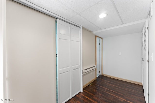 interior space featuring a baseboard heating unit, wood-type flooring, a drop ceiling, and a closet