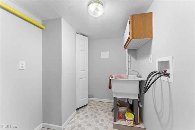 washroom with washer hookup, cabinets, and a textured ceiling