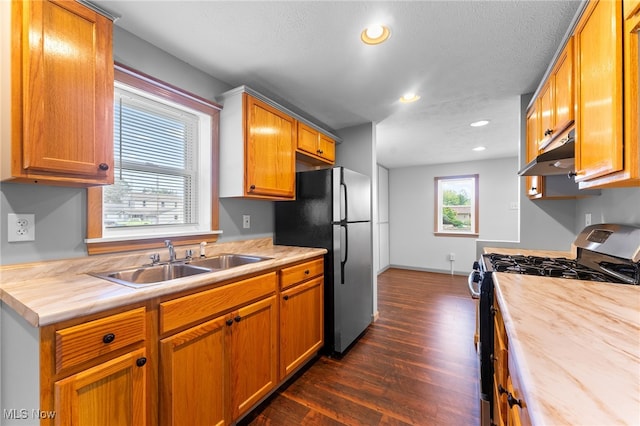 kitchen with dark wood-type flooring, gas range oven, butcher block counters, and sink