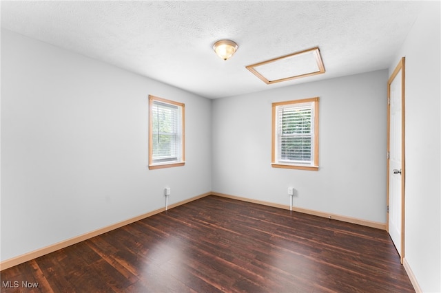 empty room with dark hardwood / wood-style floors and a textured ceiling