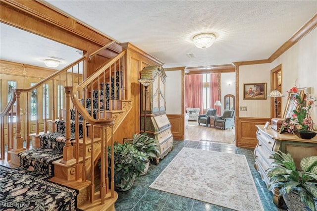 interior space with ornamental molding, a textured ceiling, and wood walls