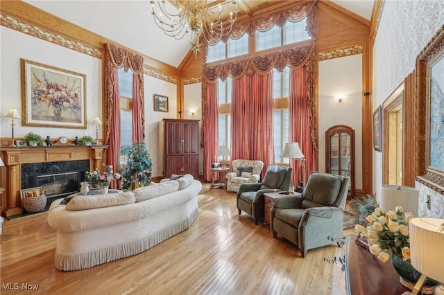 living room with a chandelier, a fireplace, high vaulted ceiling, and light hardwood / wood-style floors