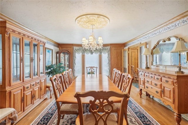 dining space featuring crown molding, a notable chandelier, a textured ceiling, and light hardwood / wood-style flooring