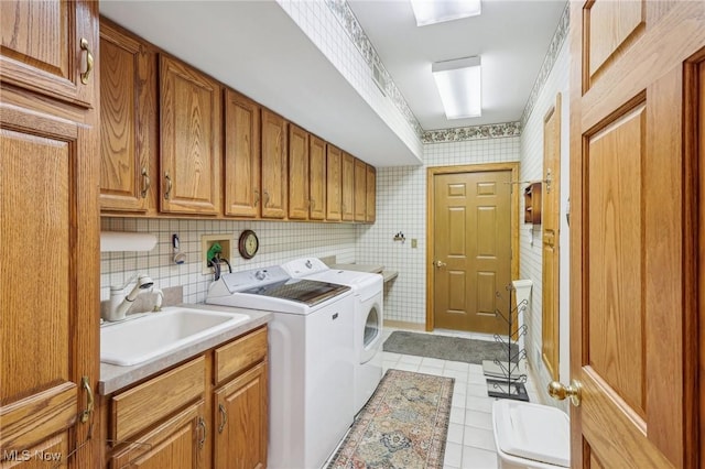 laundry room featuring sink, crown molding, light tile patterned floors, independent washer and dryer, and cabinets