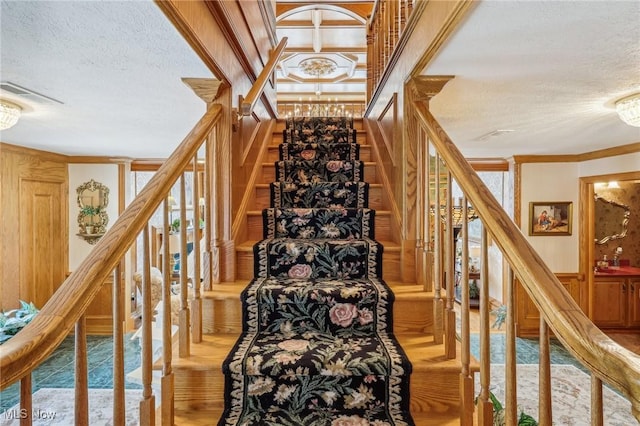 staircase featuring ornate columns, crown molding, and a textured ceiling