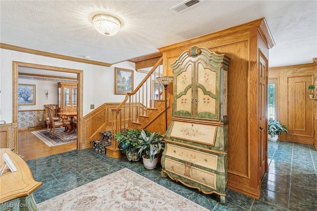 stairway featuring ornamental molding and a textured ceiling