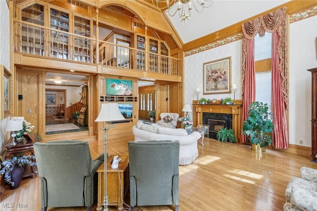 living room featuring hardwood / wood-style flooring, a high end fireplace, a chandelier, and high vaulted ceiling