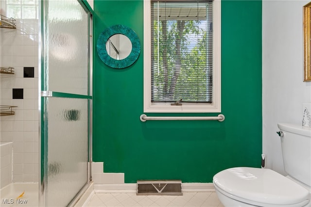 bathroom with tile patterned flooring, toilet, and a shower with shower door