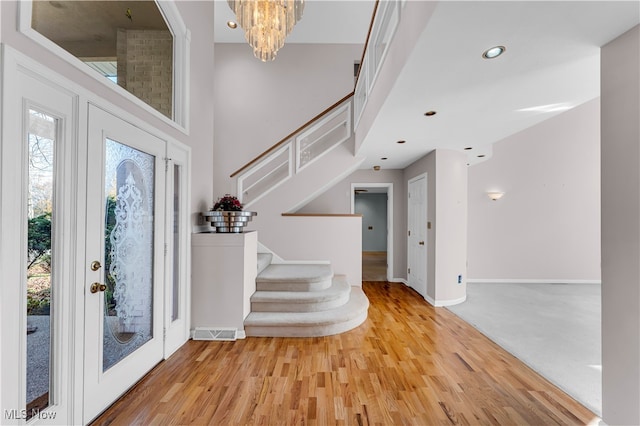 foyer with a towering ceiling, light colored carpet, and an inviting chandelier