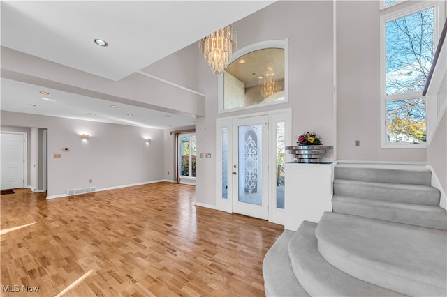 foyer entrance featuring hardwood / wood-style floors, a high ceiling, and an inviting chandelier