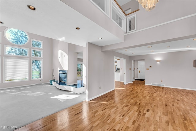 unfurnished living room with an inviting chandelier and light hardwood / wood-style flooring