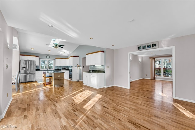 kitchen with a kitchen island, stainless steel fridge, a breakfast bar area, white cabinets, and light wood-type flooring