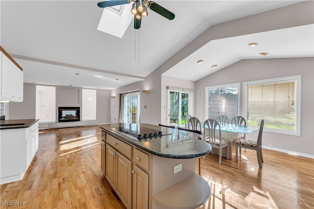 kitchen featuring ceiling fan, white cabinets, a center island, light hardwood / wood-style floors, and lofted ceiling