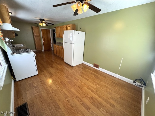 kitchen with hardwood / wood-style flooring, white appliances, sink, ceiling fan, and a textured ceiling