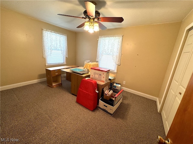 misc room with dark carpet, ceiling fan, and a healthy amount of sunlight