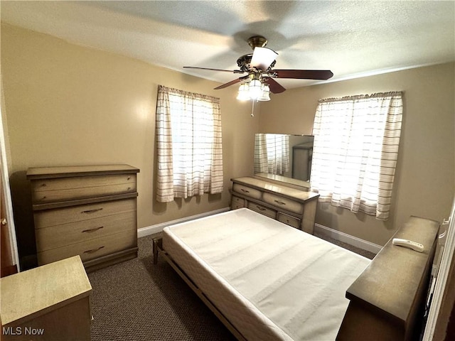 bedroom featuring dark colored carpet, ceiling fan, a textured ceiling, and baseboards