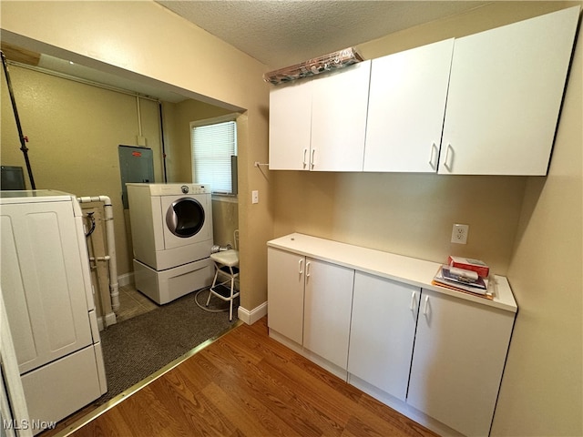 washroom featuring a textured ceiling, cabinets, separate washer and dryer, and light hardwood / wood-style floors