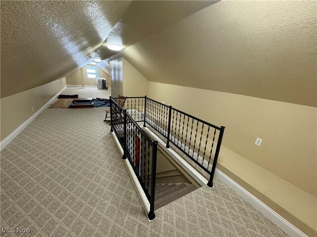 interior space with vaulted ceiling, carpet, and a textured ceiling