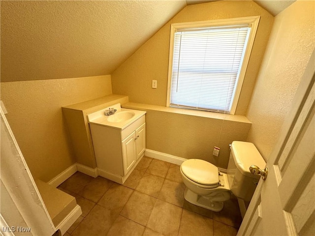 bathroom with a textured ceiling, a textured wall, lofted ceiling, toilet, and vanity