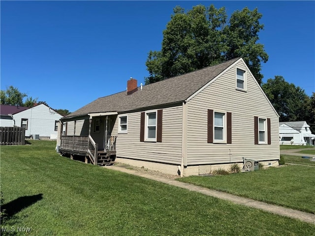 rear view of property with roof with shingles, a yard, and a chimney