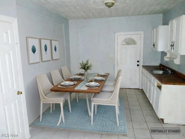 tiled dining room with a textured ceiling and sink