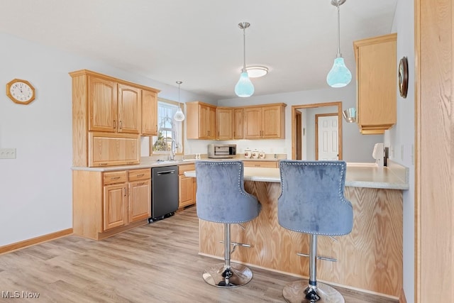 kitchen with pendant lighting, appliances with stainless steel finishes, a breakfast bar area, light brown cabinets, and light hardwood / wood-style floors