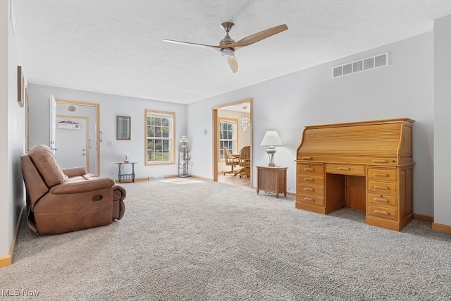 living area featuring ceiling fan, carpet, and a textured ceiling