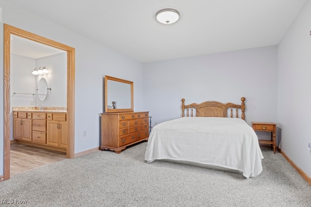 bedroom featuring light colored carpet, ensuite bath, and sink