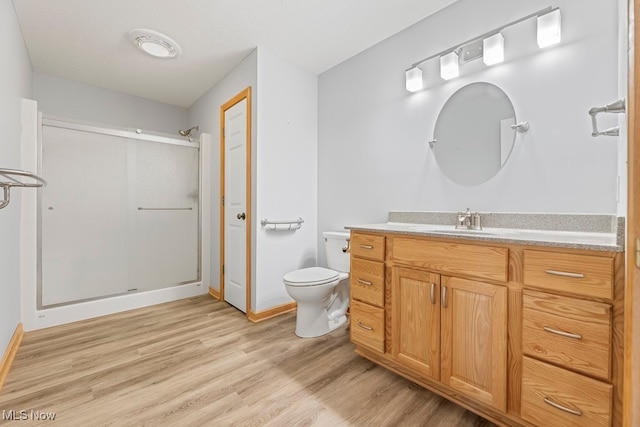 bathroom with walk in shower, toilet, wood-type flooring, and vanity