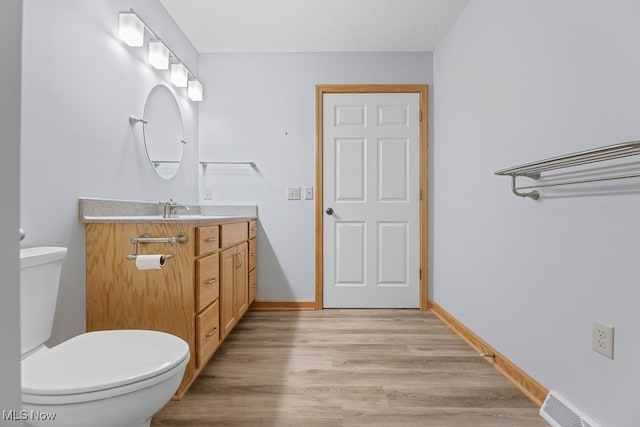 bathroom with vanity, toilet, and wood-type flooring